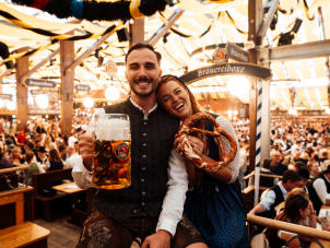 Besucher im Festzelt mit Breze und Maß Oktoberfestbier